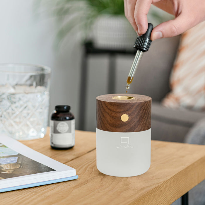 gingko american walnut effect smart diffuser being refilled with essential oils with a pippette