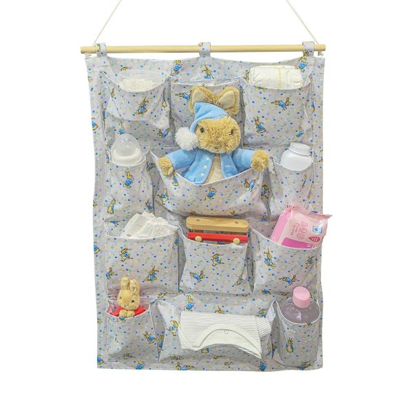Peter Rabbit Nursery Organiser. Featuring 12 individual pockets over 4 shelves, rope to hang the organiser on the wall being used with baby products and a cuddly peter rabbit inside the compartments. 