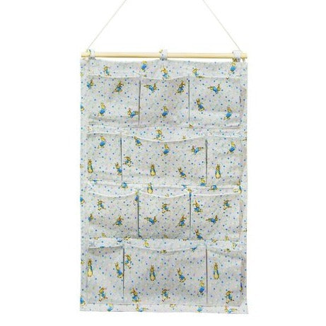 Peter Rabbit Nursery Organiser. Featuring 12 individual pockets over 4 shelves, rope to hang the organiser on the wall. The colours are light grey with a pastel polka dot and peter rabbits repeated across  the fabric
