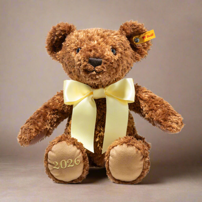Brown teddy bear with a yellow bow and '2026' on a white background