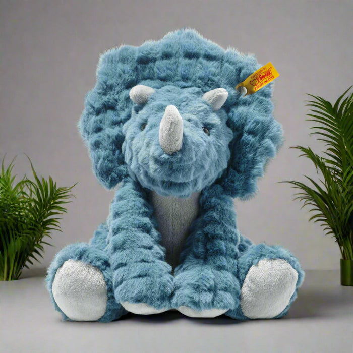 Blue plush triceratops toy with a visible brand tag on a white background