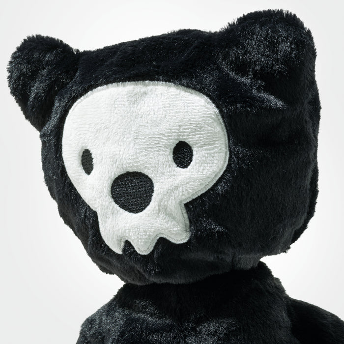 Black plush toy with skull face design on a white background