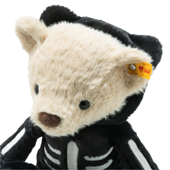 Plush bear toy in a skeleton costume with a visible Steiff tag on a white background
