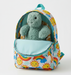 Colorful backpack with a teddy bear inside on a white background