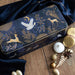 Decorative tin box with gold animal illustrations on a wooden surface with festive items.