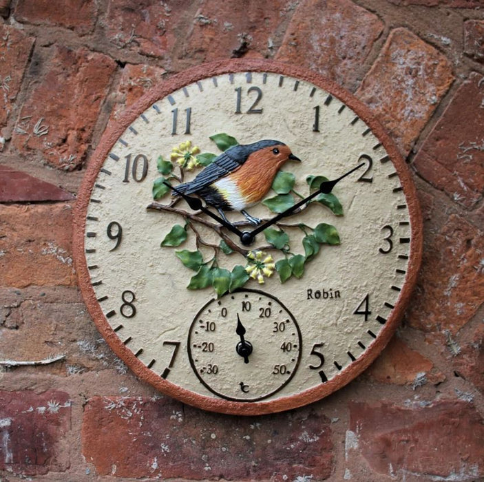 Decorative clock with a robin design on a brick wall