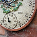 Decorative wall clock with floral design and thermometer on a rustic background