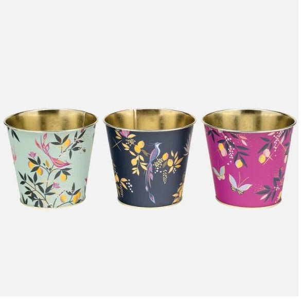 Sara Miller Stacking Metal Plant Pots With Floral and Leaf Designs Against A Dark Pink, Light Blue And Navy Background