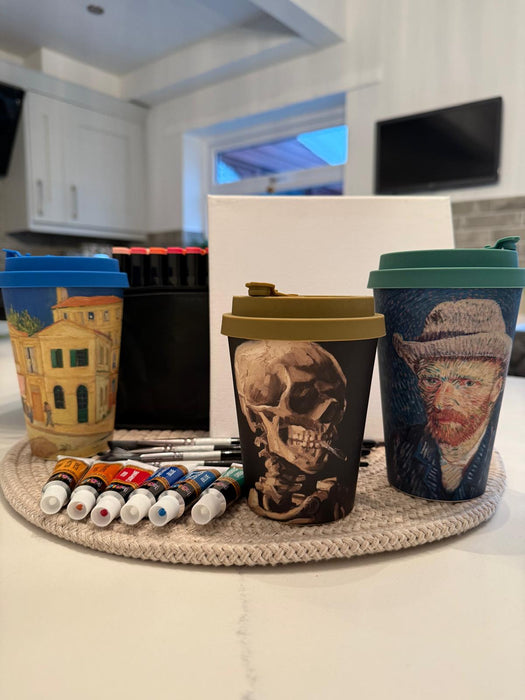 Four reusable coffee cups with different designs on a kitchen counter.
