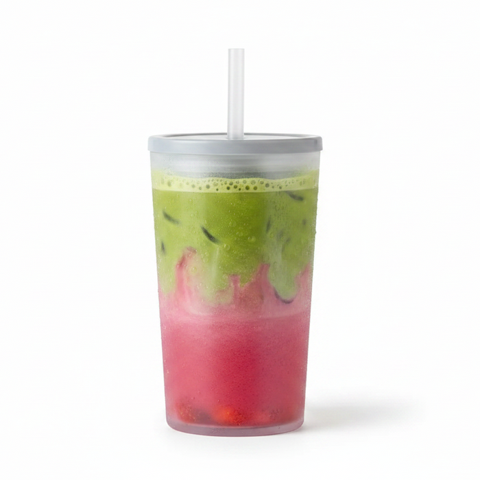 A clear plastic travel tumbler with a silver lid and white straw, filled with a layered pink and green iced drink, isolated on a white background.