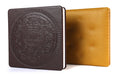 Two leather-bound books, one black with embossed design and the other brown, on a white background.