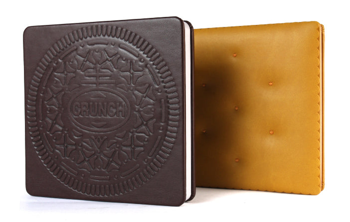 Two leather-bound books, one black with embossed design and the other brown, on a white background.