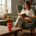 Woman reading a book in a cozy living room with a red cup on a table.