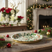 Decorative tray with holly design on a festive table with Christmas decorations.