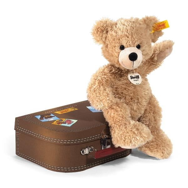 Plush teddy bear with a suitcase on a white background