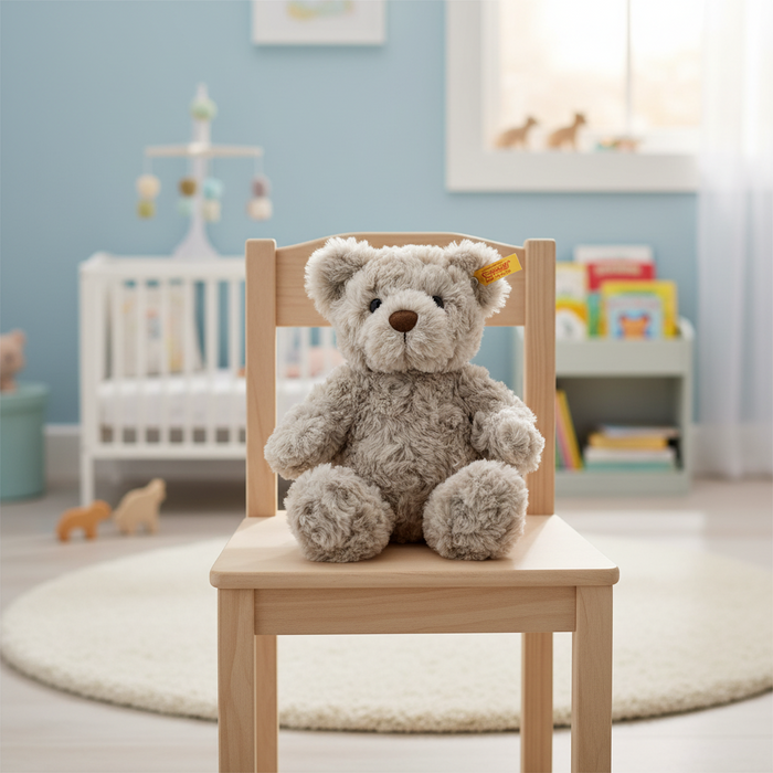 Teddy bear sitting on a wooden chair in a child's room with blue walls and toys.
