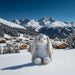 Plush bunny toy in the snow with a mountain village background