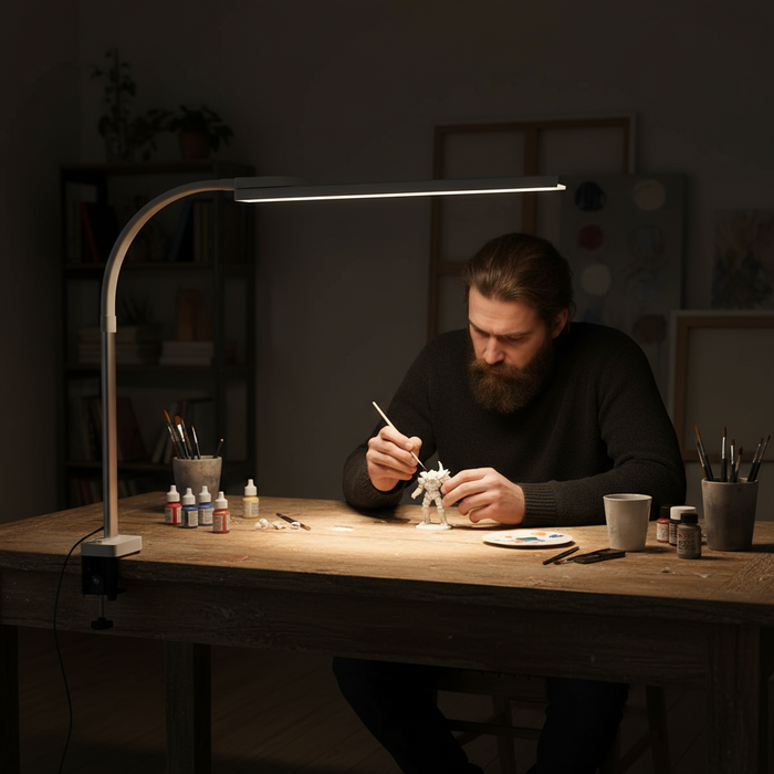 Man working on a craft project at a desk with a lamp illuminating his workspace.