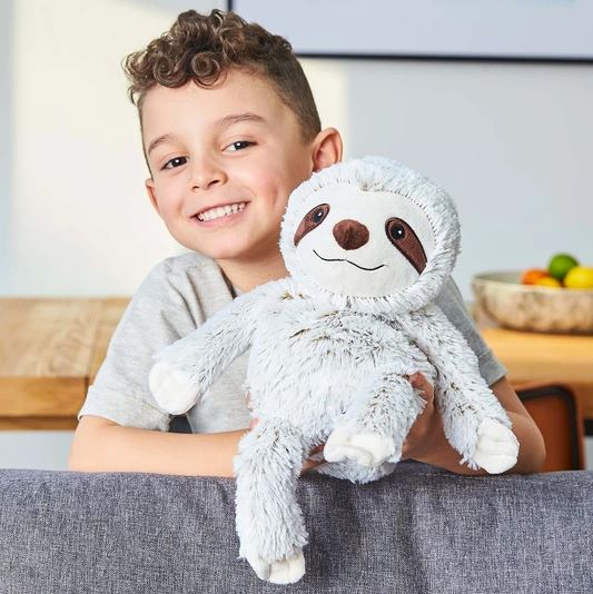 young boy holding warmies grey sloth heat-up toy