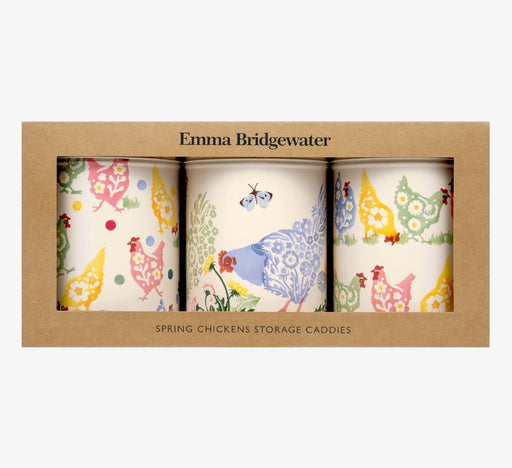 A off white set of three canisters with pastel coloured hens printed repeatedly around the tin with matching pastel coloured polka dots and butterflies in Emma Bridgewater packaging.