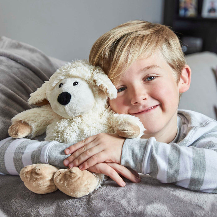 young boy holding warmies sheep heat-up soft toy