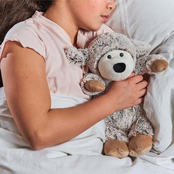young girl holding warmies grey sheep heat-up soft toy