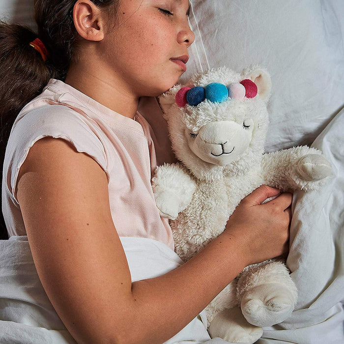 young girl sleeping with Warmies microwavable soft llama toy with multicoloured pom pom headband