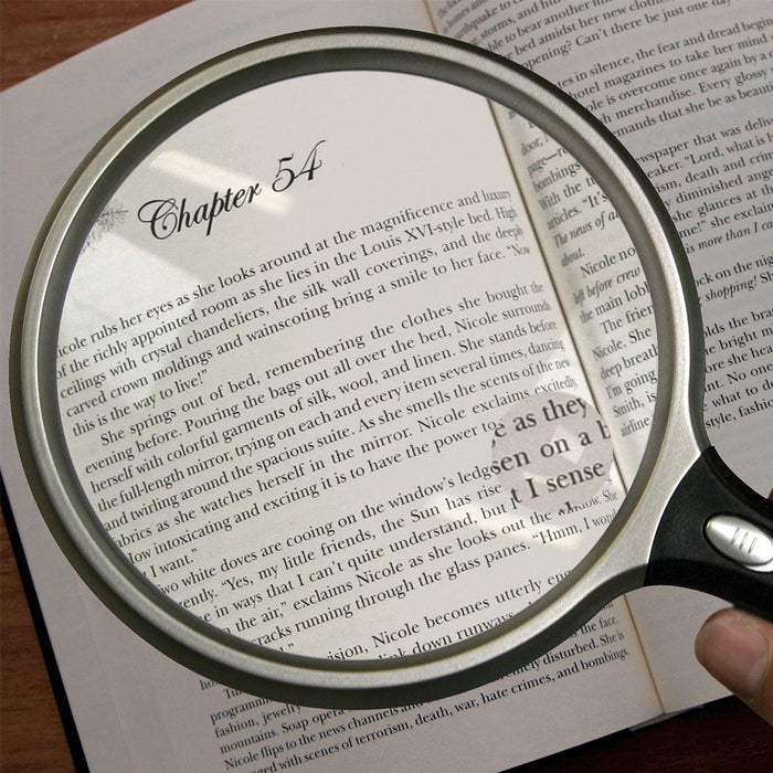 5 inch round LED magnifier with black handle inspecting a book