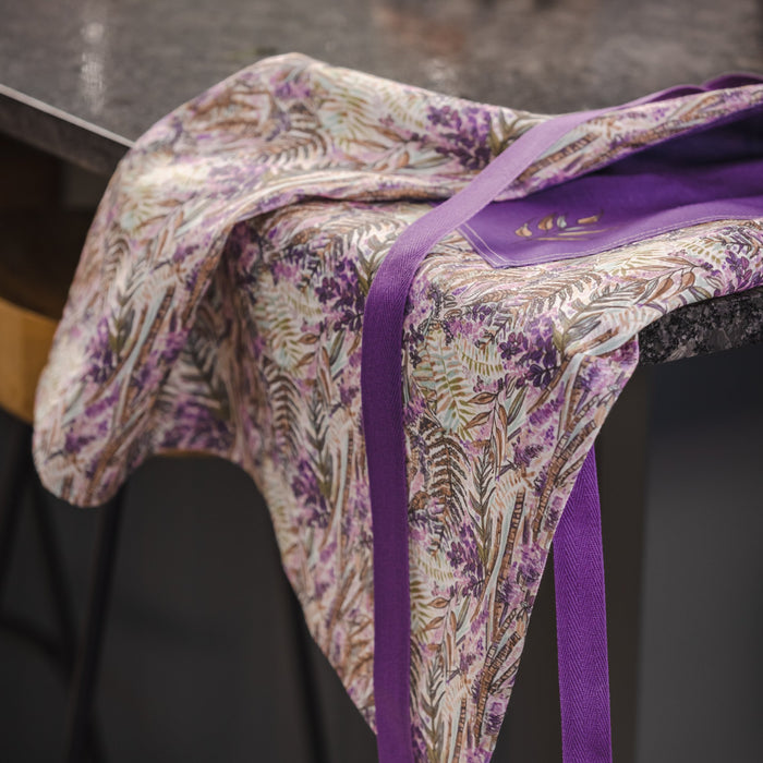 Floral Purple Heather Apron Laid On A Dark Marble Kitchen Counter