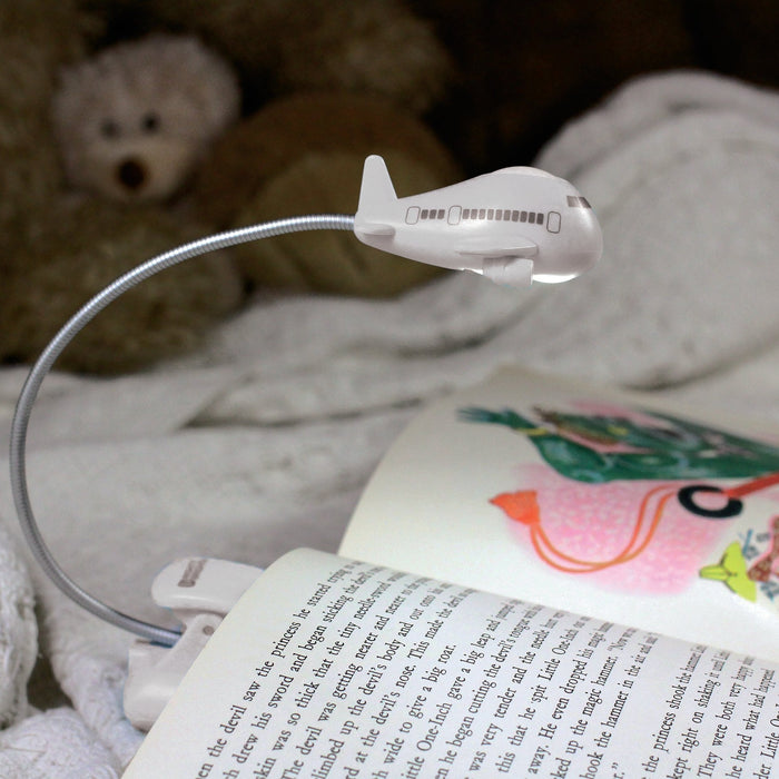 Airplane shaped light lighting up a children's book. 