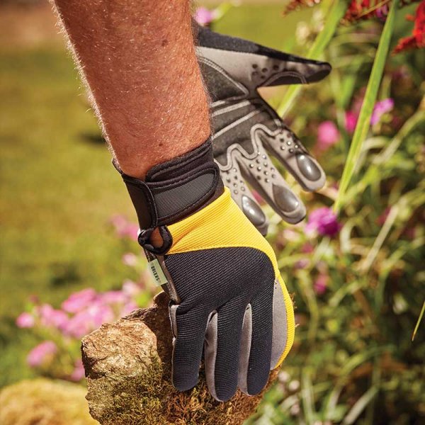 Advanced grip gardening gloves being used to pick up rocks from a garden flower bed. 