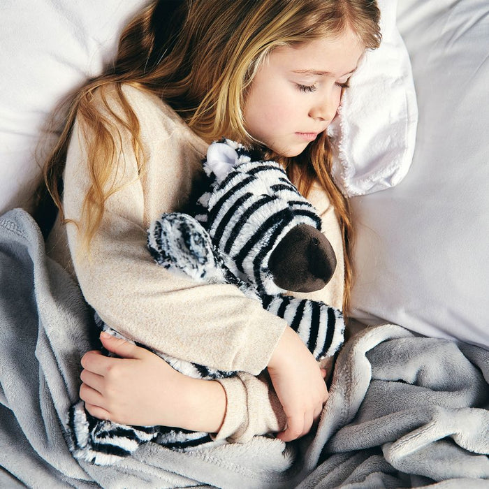 young girl sleeping with warmies heat-up zebra toy