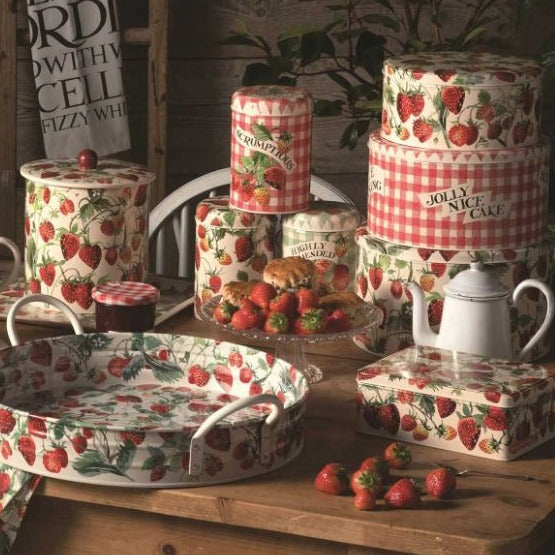 Rustic table scene with Emma Bridgewater Strawberries cake tins, storage tins, tray and biscuit tin. The table features fresh strawberries with scones and jam.