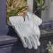 A pair of ecru coloured leather gloves placed on a grey wooden windowsill of a shed. 