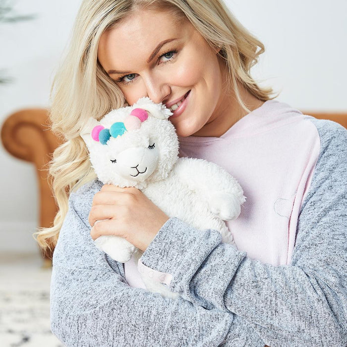 blonde woman holding warmies llama with pom poms hot water bottle