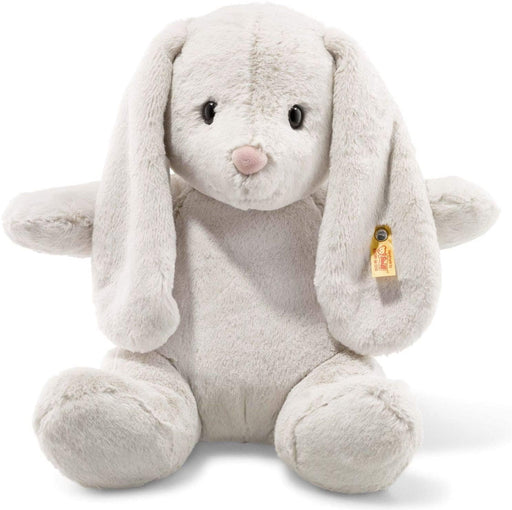 A light grey bunny rabbit plush with long floppy ears with a steiff tag in the ear and a pale pink nose. 