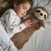 A little girl in bed asleep next to her sloth hot water bottle 