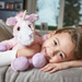 young girl holding Warmies pink unicorn heatable soft toy